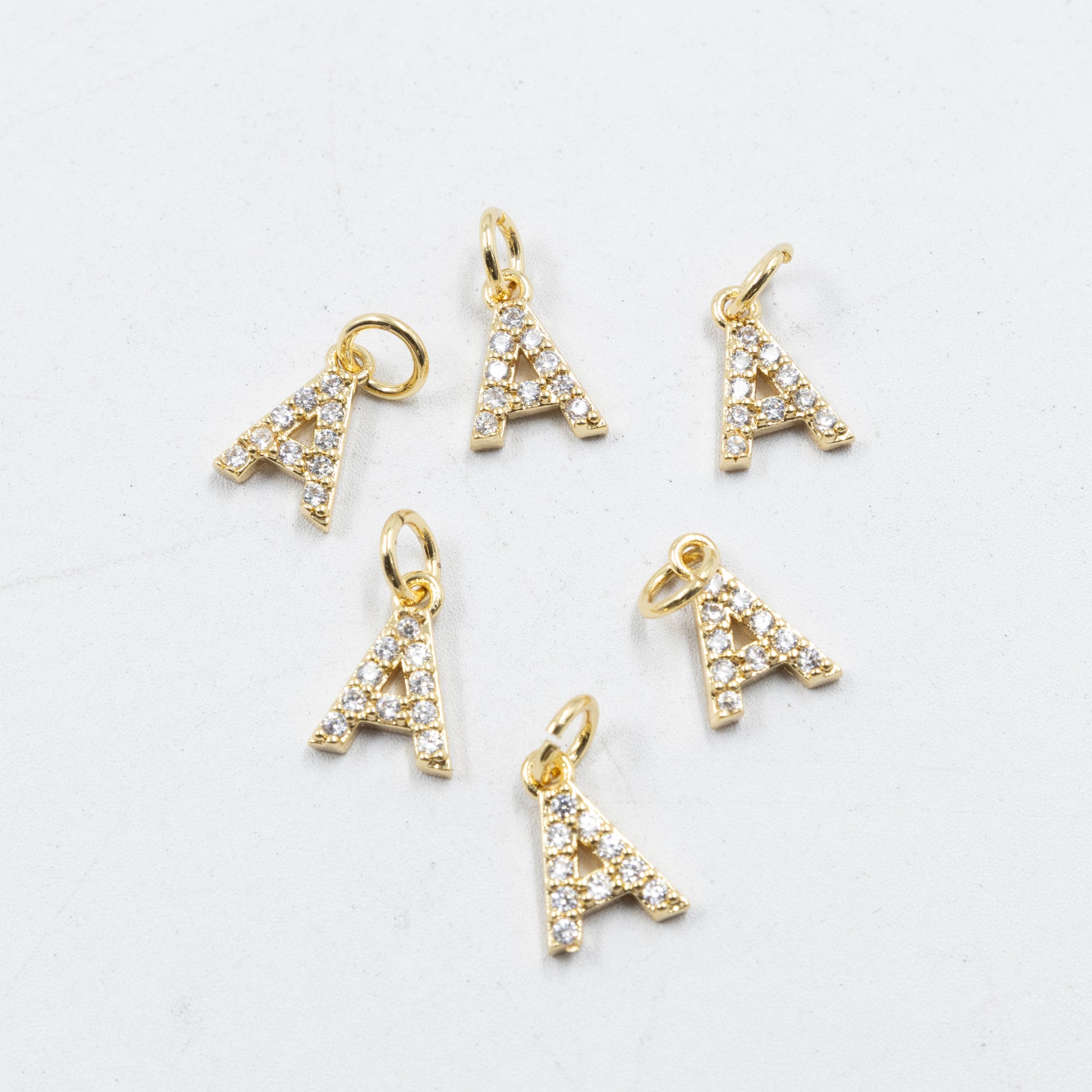 Paquete de 6 Dijes de Letras con piedras M1 Oro Laminado