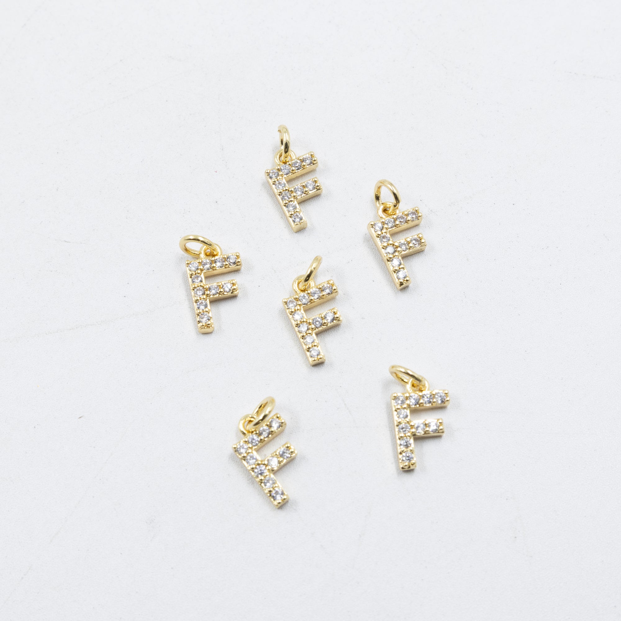 Paquete de 6 Dijes de Letras con piedras M1 Oro Laminado